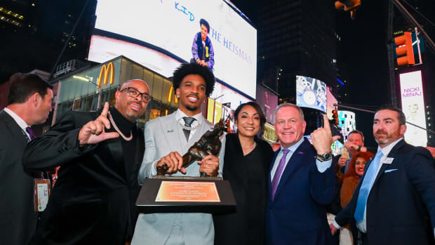 Dec 9, 2023; New York, New York, USA; Heisman Trophy winner Jayden Daniels poses with his parents, Javon Daniels, left, Regina Jackson, right and LSU coach Brian Kelly, far right, under an LSU billboard in Times Square. Mandatory Credit: Todd Van Emst/Heisman Trust/Pool-USA TODAY Sports