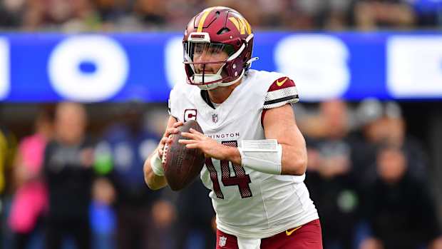 Washington Commanders quarterback Sam Howell (14) moves out to pass against the Los Angeles Rams during the first half at SoFi Stadium.