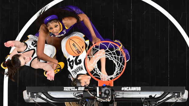 Iowa’s Caitlin Clark and LSU’s Angel Reese fight for a rebound.