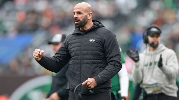 Robert Saleh pumps his fist while holding his headset in the other hand