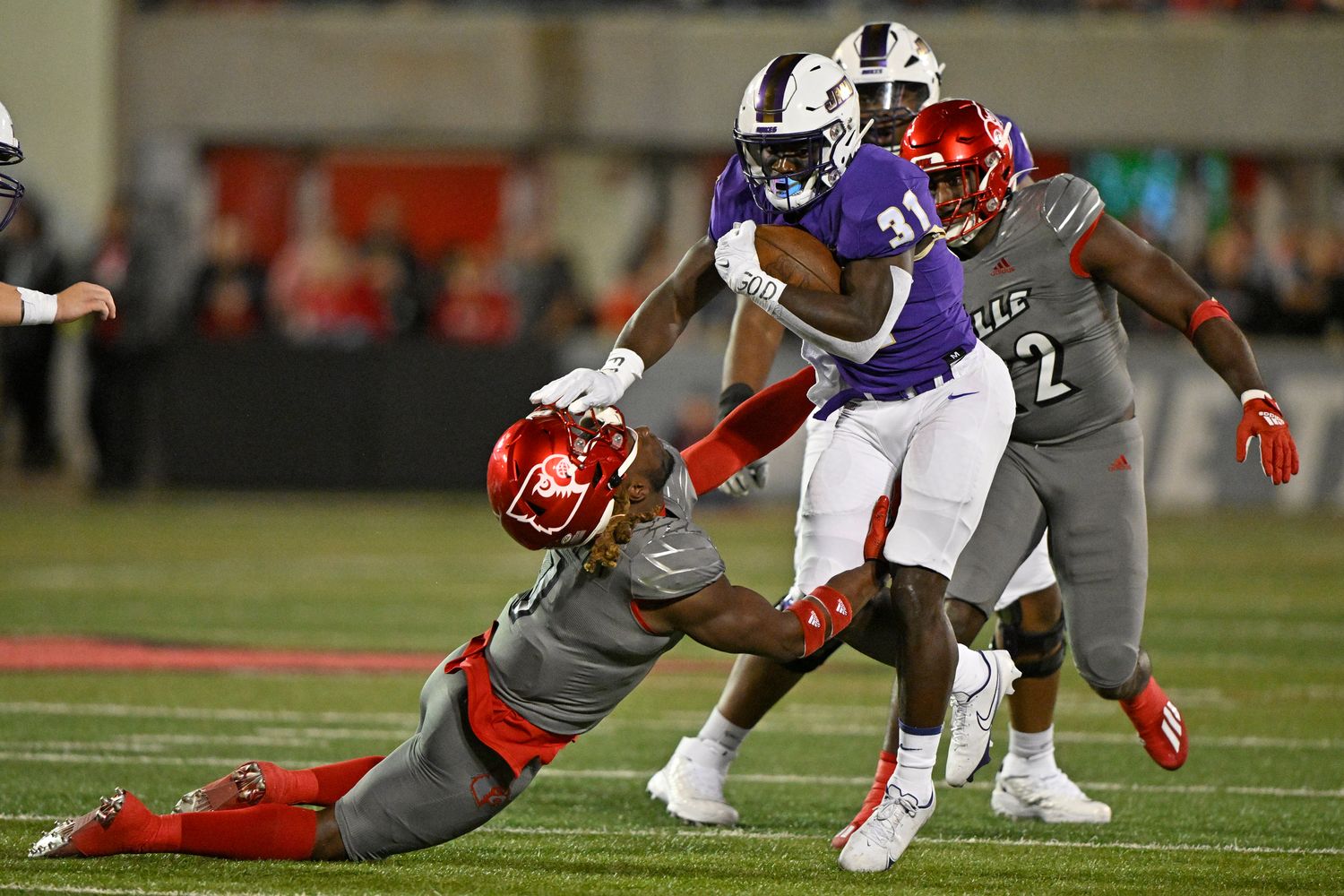 Nov 5, 2022; Louisville, Kentucky, USA; James Madison Dukes running back Percy Agyei-Obese (31) pushes past the tackle of Louisville Cardinals linebacker Monty Montgomery (7) during the first quarter at Cardinal Stadium. Mandatory Credit: Jamie Rhodes-USA TODAY Sports  