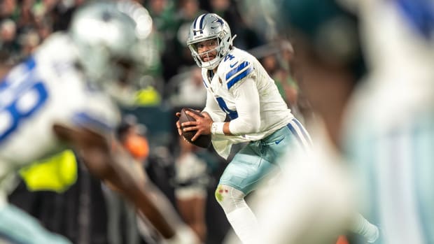 Dak Prescott runs on the field as Cowboys players run in front of him, blurry