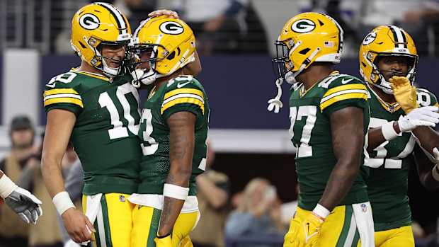 Jordan Love pats Dontayvion Wicks on the head in celebration as two other Packers players stand next to them, too.