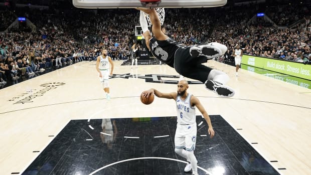 Jan 27, 2024; San Antonio, Texas, USA; San Antonio Spurs forward Keldon Johnson (3) hangs from the rim after dunking over Minnesota Timberwolves guard Jordan McLaughlin (6) during the second half at Frost Bank Center.