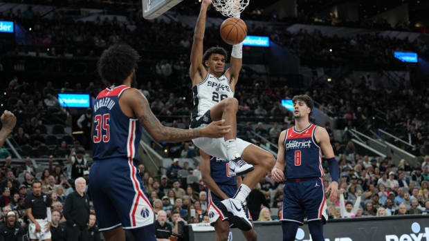 Jan 29, 2024; San Antonio, Texas, USA; San Antonio Spurs forward Dominick Barlow (26) dunks between Washington Wizards forwards Marvin Bagley III (35) and Deni Avdija (8) in the first half at Frost Bank Center.