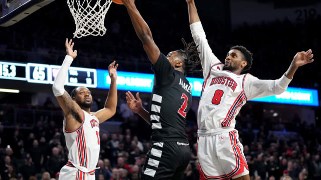 Cincinnati Bearcats guard Jizzle James (2) rises to the basket as Houston Cougars guard Mylik Wilson (8) defends in the second half of an NCAA college basketball game between the Houston Cougars and the Cincinnati Bearcats, Saturday, Feb. 10, 2024, at Fifth Third Arena in Cincinnati.