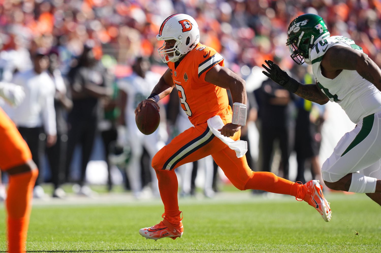 Broncos' QB Russell Wilson runs away from pressure by the Jets' defense