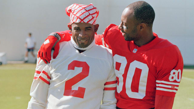Jerry Rice, right, puts his arm around Deion Sanders on the practice field as members of the San Francisco 49ers