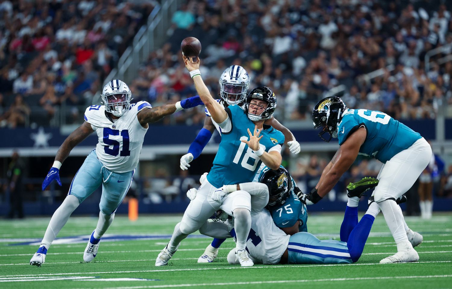 Aug 12, 2023; Arlington, Texas, USA; Jacksonville Jaguars quarterback Nathan Rourke (18) runs away from Dallas Cowboys defenders and throws a touchdown pass during the second half at AT&T Stadium. Mandatory Credit: Kevin Jairaj-USA TODAY Sports