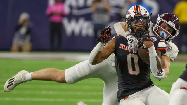 Dec 27, 2023; Houston, TX, USA; Oklahoma State Cowboys running back Ollie Gordon II (0) is tackled by Texas A&M Aggies linebacker Sam Mathews (12) in the second half at NRG Stadium. Mandatory Credit: Thomas Shea-USA TODAY Sports 