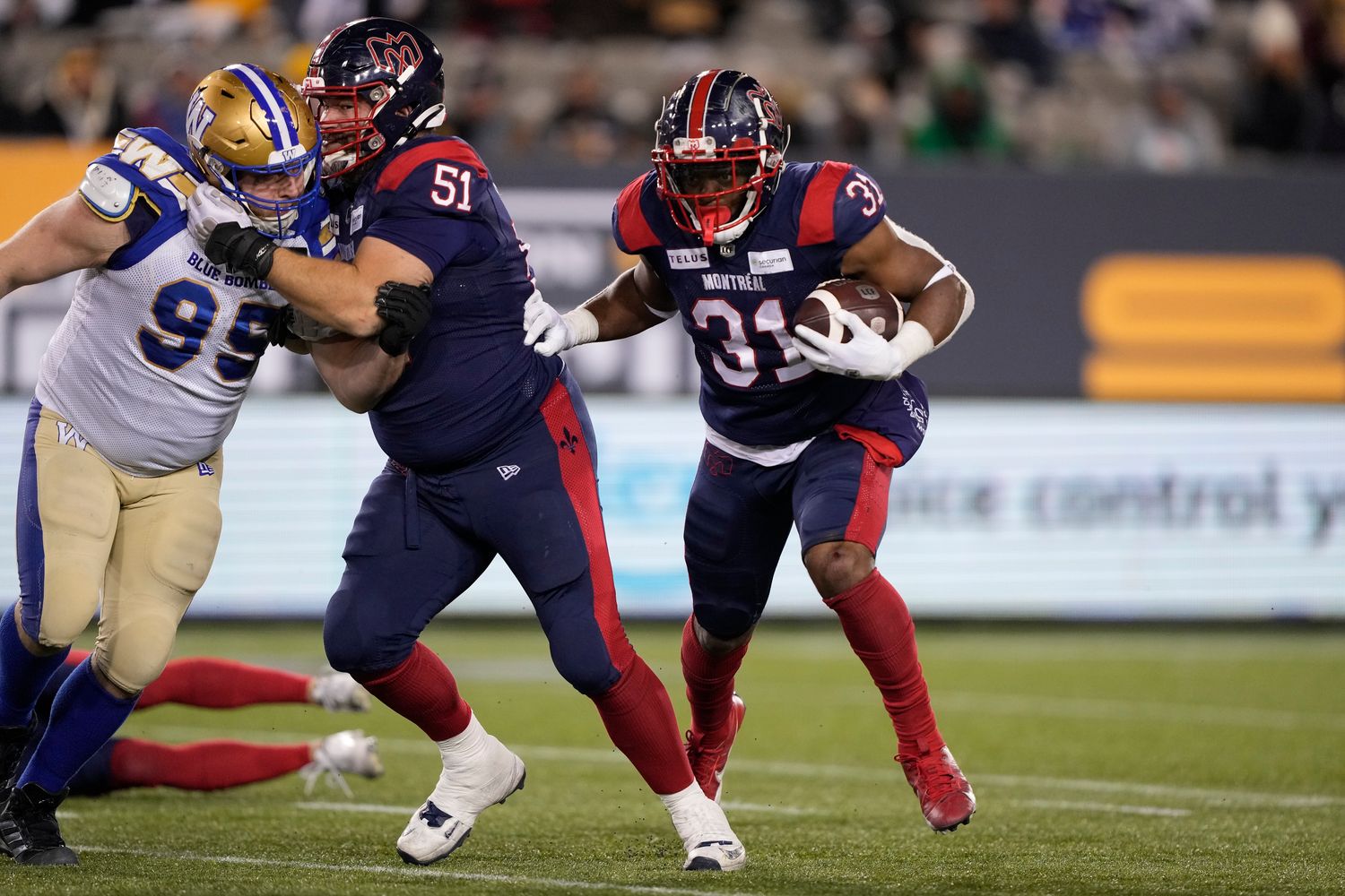 Nov 19, 2023; Hamilton, Ontario, CAN; Montreal Alouettes running back William Stanback (31) runs behind the block of offensive lineman Kristian Matte (51) on Winnipeg Blue Bombers defensive lineman Jake Thomas (95) during the 110th Grey Cup at Tim Hortons Field. Mandatory Credit: John E. Sokolowski-USA TODAY Sports  