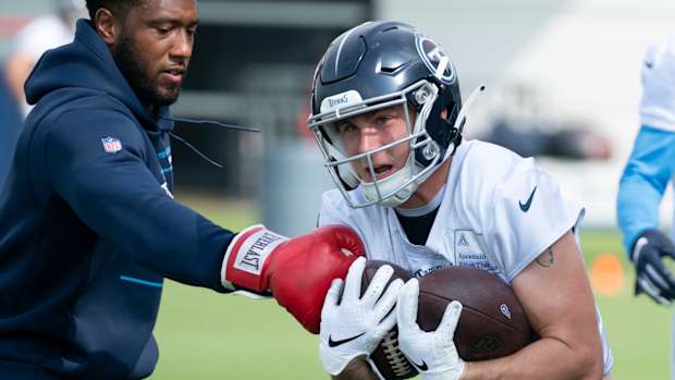 Tennessee Titans offensive skill assistant Erik Frazier tries to punch the ball away from wide receiver Mason Kinsey (12) during practice at Saint Thomas Sports Park Tuesday, June 7, 2022, in Nashville, Tenn.