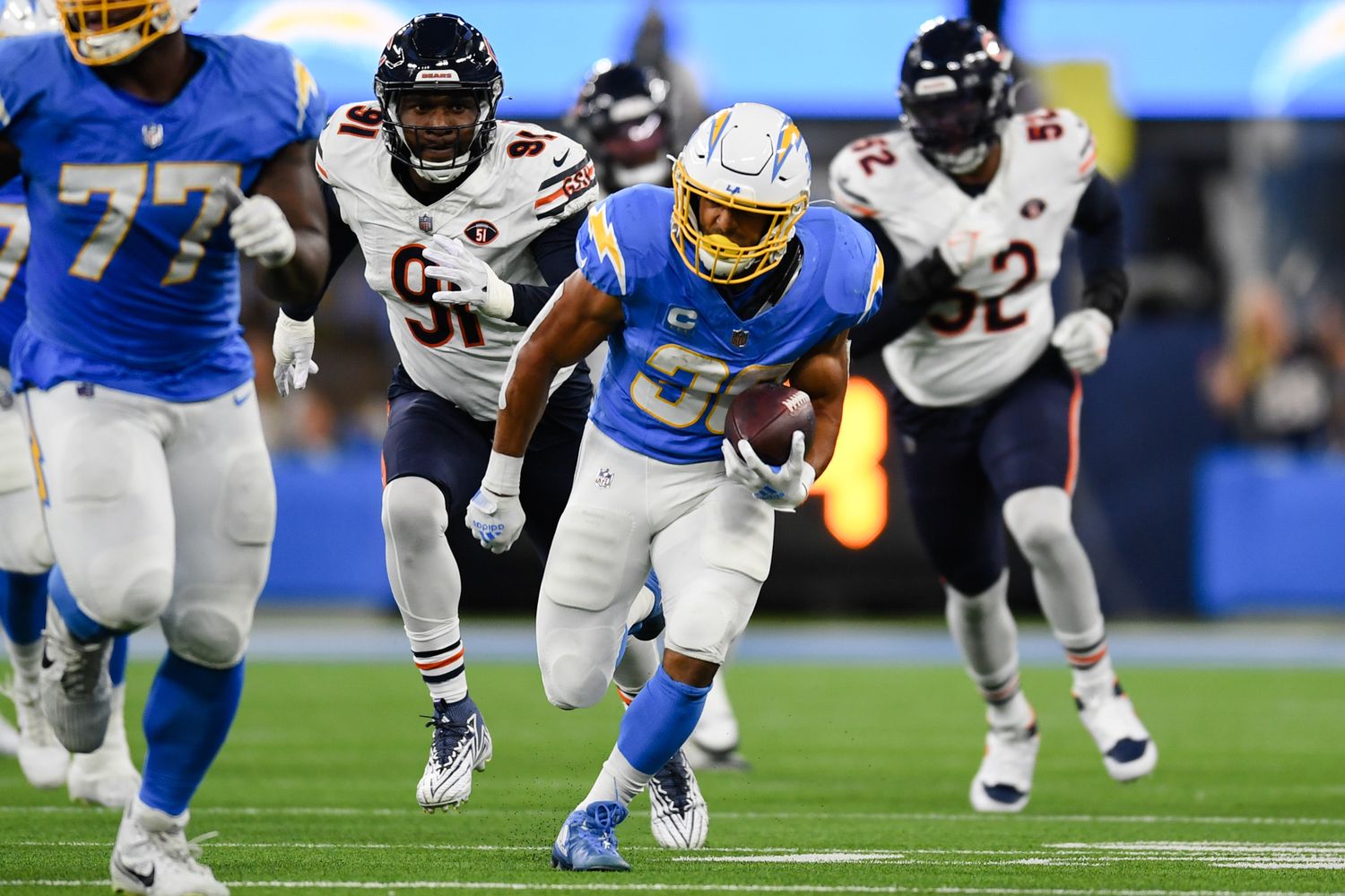 Los Angeles Chargers running back Austin Ekeler (30) runs the ball against Los Angeles Chargers defensive tackle Christopher Hinton (91) and linebacker Khalil Mack (52) during the second quarter at SoFi Stadium.