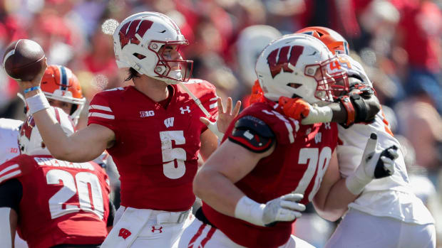 Graham Mertz throwing the football against Illinois with a pass-rusher in his face.