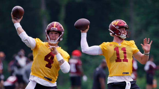 Washington Commanders quarterbacks Taylor Heinicke (4) and Carson Wentz (11) throw during a team practice session.