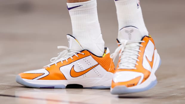 View of Devin Booker's orange and white Nike shoes.