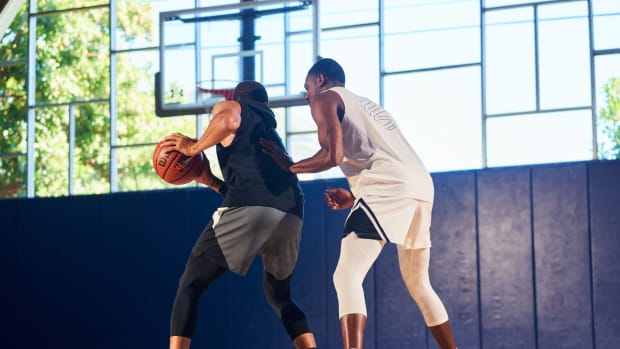 De'Aaron Fox and Stephen Curry work out in a basketball gym.