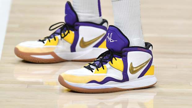 View of white, purple, and gold Nike Kyrie shoes.