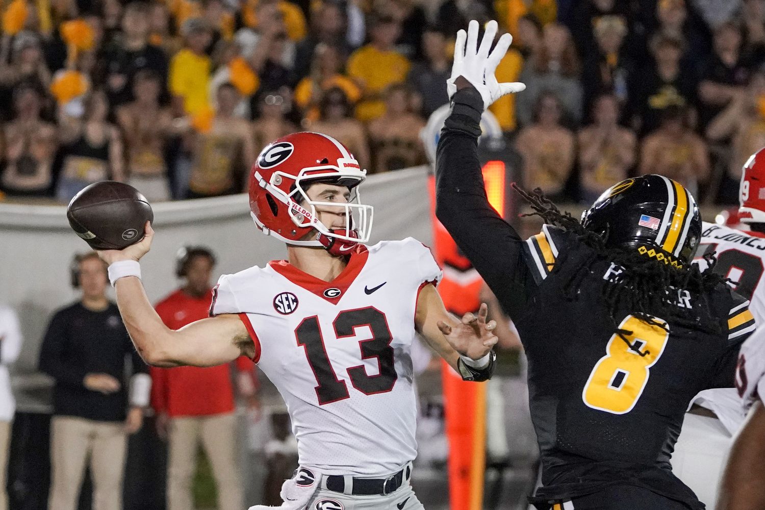 Georgia Bulldogs quarterback Stetson Bennett (13) throws a pass as Missouri Tigers linebacker Ty'Ron Hopper (8) tries to block during the second half at Faurot Field at Memorial Stadium.