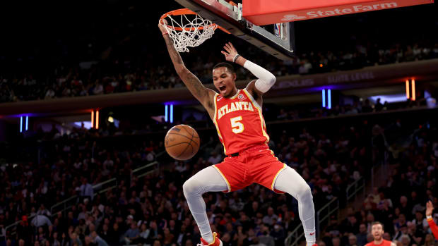 Hawks guard Dejounte Murray hangs on the rim after dunking.
