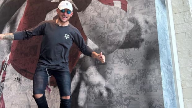 Johnny Manziel poses in front of his picture at a Texas A&M football game.