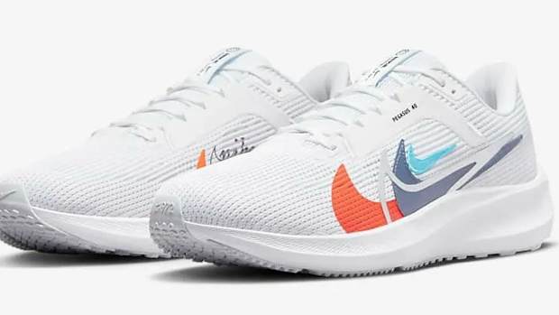 Side view of white and orange Nike running shoes.
