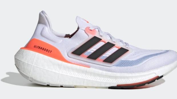 Side view of white, black, and orange adidas running shoe.