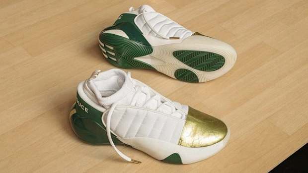 Side view of James Harden's white, green, and gold adidas shoes.