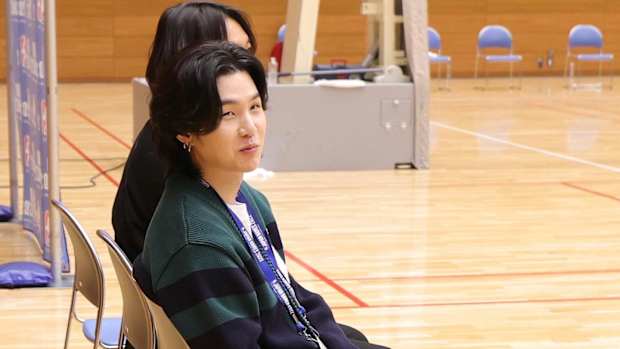 Suga sits on sidelines of Warriors practice.