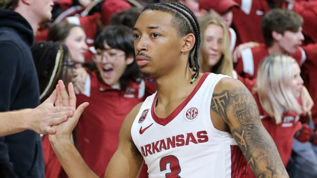 Nick Smith, Jr. high fives fans following a game in Bud Walton Arena.