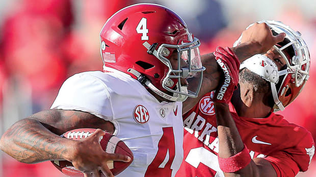 Alabama Crimson Tide quarterback Jalen Milroe stiff-arms Arkansas Razorbacks defensive back Dwight McGlothern on his way to a 77-yard run Saturday afternoon at Razorback Stadium. 