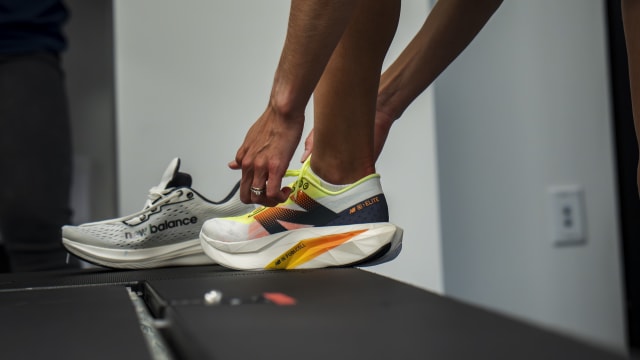 Emily Sisson ties a white and black New Balance running shoe.