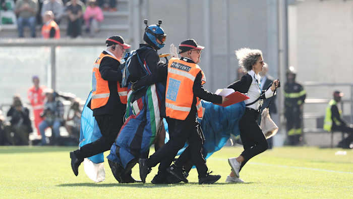 A man in a parachute lands on the field during a Serie A soccer game in Italy.