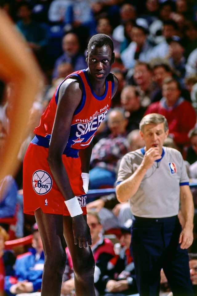 Manute Bol #10 of the Philadelphia 76ers rests against the Sacramento Kings during a game played on January 2, 1992 at Arco Arena in Sacramento, California.
