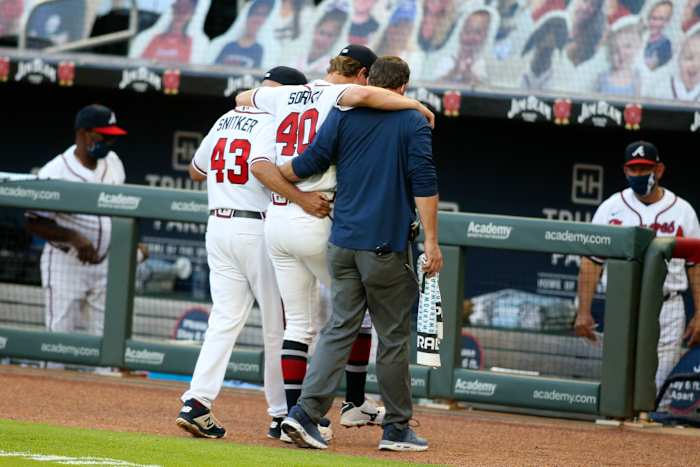 Manager Brian Snitker and one of the trainers help Mike Soroka off the field.