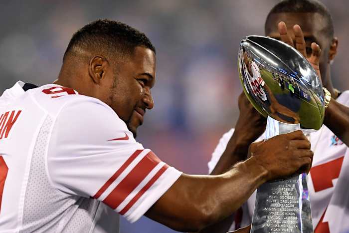 Former Giants player Michael Strahan walks onto the field with the Vince Lombardi Trophy from Super Bowl XLII during the halftime ceremony in the game against the Lions at MetLife Stadium, Sept. 18, 2017.