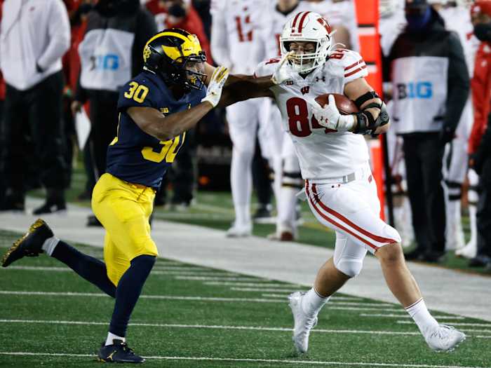 Wisconsin Badgers tight end Jake Ferguson (84) stiff arms Michigan Wolverines defensive back Daxton Hill (30) in the second half at Michigan Stadium.