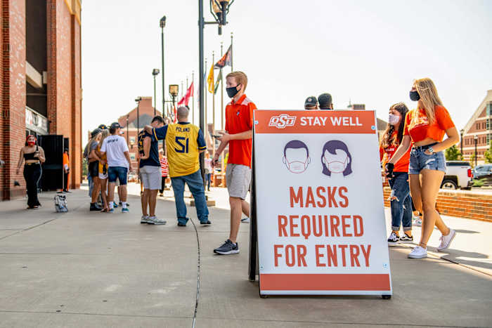A sign tells fans outside a stadium that masks are required for entry