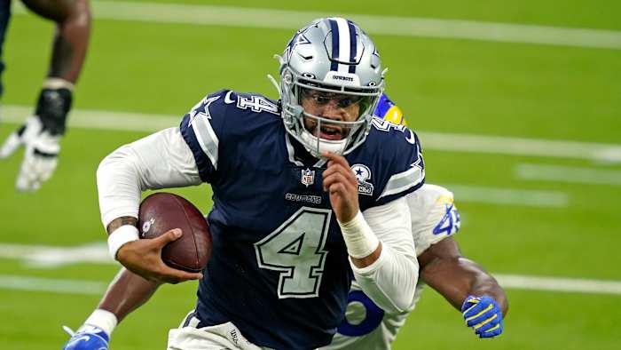 Dak Prescott runs from a Rams defender during a game
