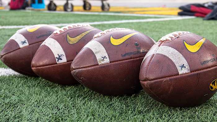 College footballs sit on ground