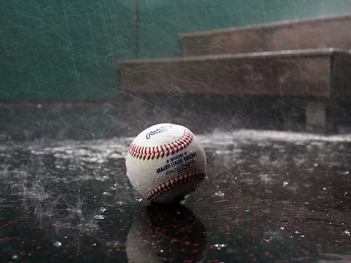 A baseball left on the ground in the rain