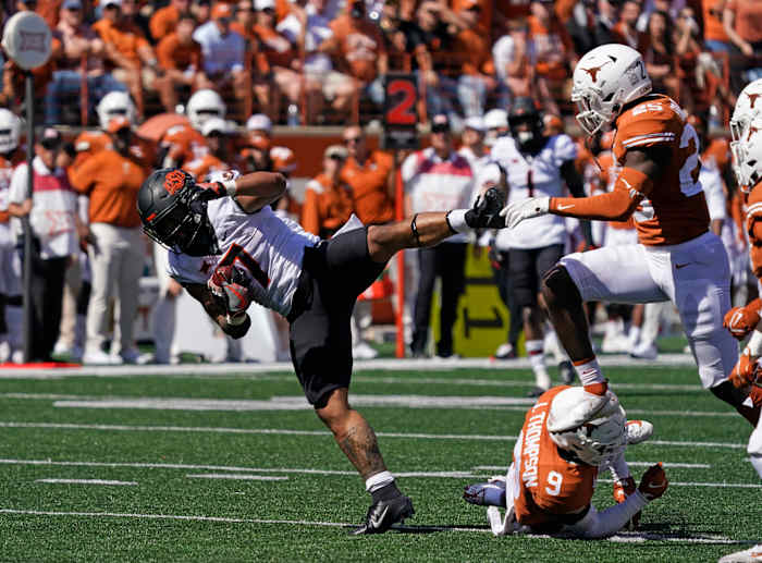 Oct 16, 2021; Austin, Texas, USA; Oklahoma State Cowboys running back Jaylen Warren (7) leaps over Texas Longhorns defensive back Josh Thompson (9) in the second half at Darrell K Royal-Texas Memorial Stadium.