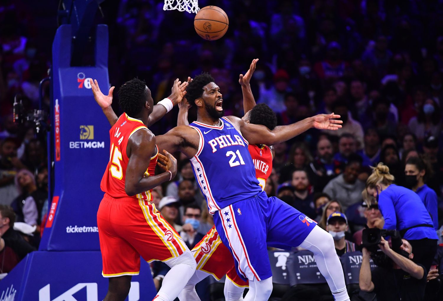 76ers center Joel Embiid reacts as he collides with Hawks center Clint Capela.