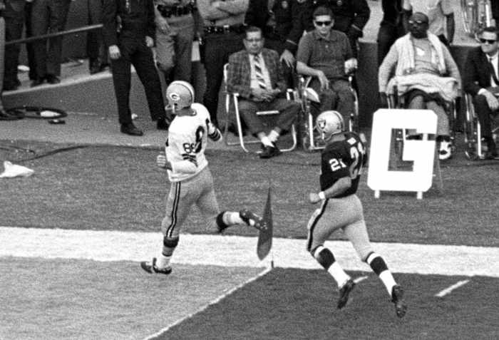 A Packers player runs past the flag at the front corner of the end zone