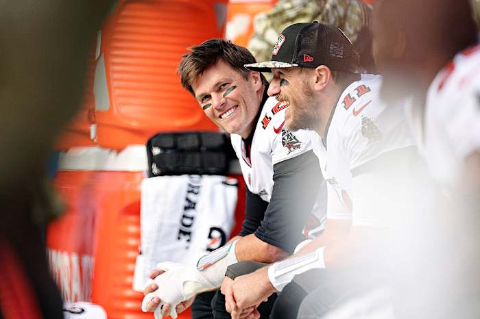 Tom Brady smiles as he looks up from the bench during a Bucs game