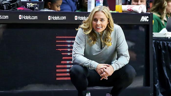 Baylor coach Nicki Collen smiles while crouching on the sideline