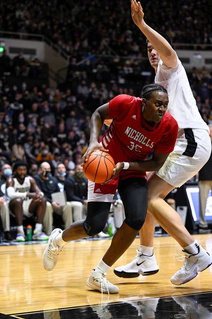 A Nicholls State player dribbles around Zach Edey.
