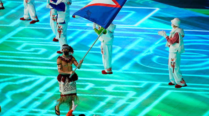 Nathan Crumpton, of American Samoa, carries his national flag into the stadium during the opening ceremony of the 2022 Winter Olympics, Friday, Feb. 4, 2022, in Beijing.