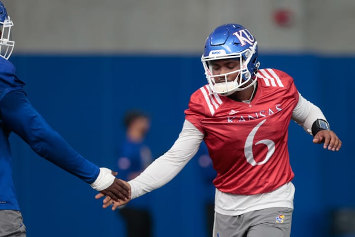 Kansas junior quarterback Jalon Daniels (6) slaps a teammates hand practice Tuesday morning in Lawrence.