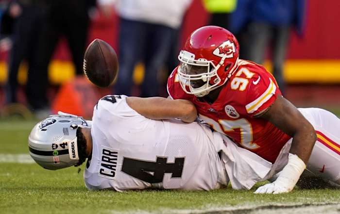 Dec 12, 2021; Kansas City, Missouri, USA; Las Vegas Raiders quarterback Derek Carr (4) fumbles the ball as he is tackled by Kansas City Chiefs defensive end Alex Okafor (97) during the second half at GEHA Field at Arrowhead Stadium. Mandatory Credit: Jay Biggerstaff-USA TODAY Sports